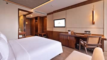 Una habitación de hotel con una cama, un escritorio, una silla, un televisor y un armario.