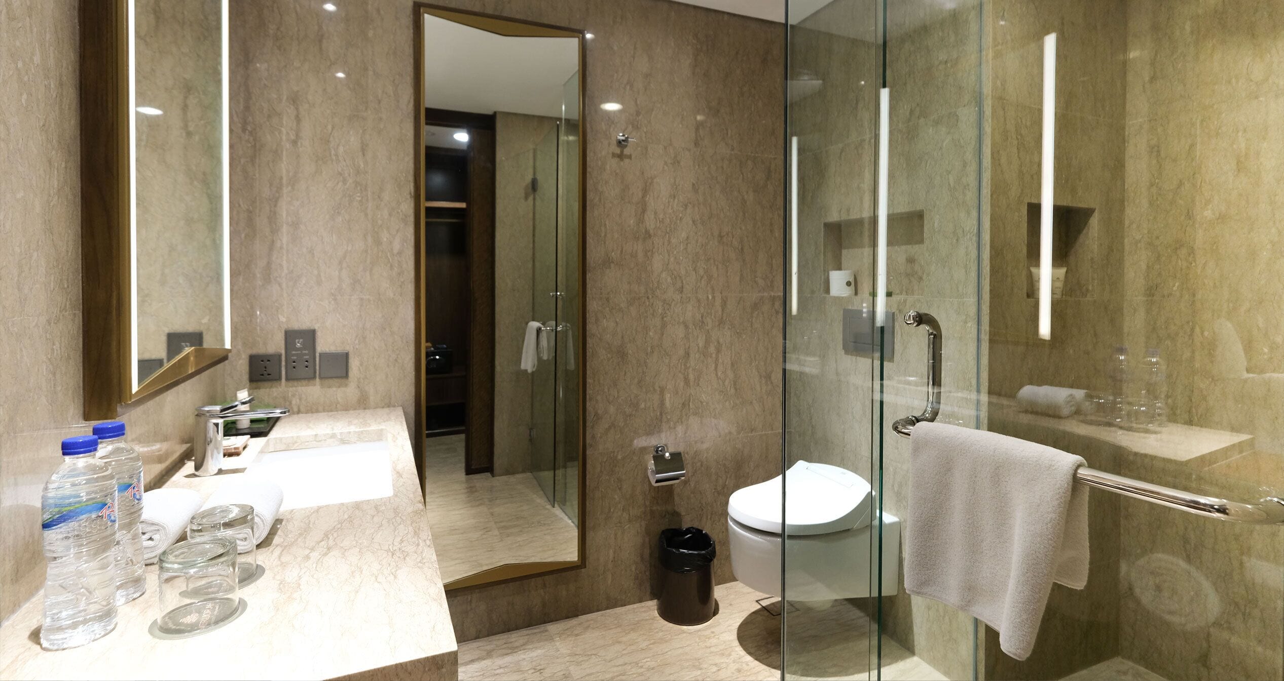 A modern bathroom with a glass shower enclosure, a toilet, and a sink with toiletries.