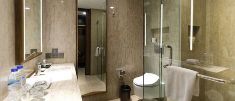 A modern bathroom with a glass shower enclosure, a toilet, and a sink with toiletries.