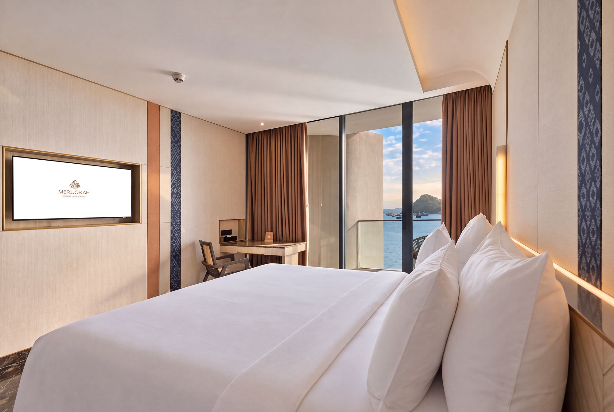 Een hotelkamer met een bed, een bureau, een stoel en uitzicht op zee.
