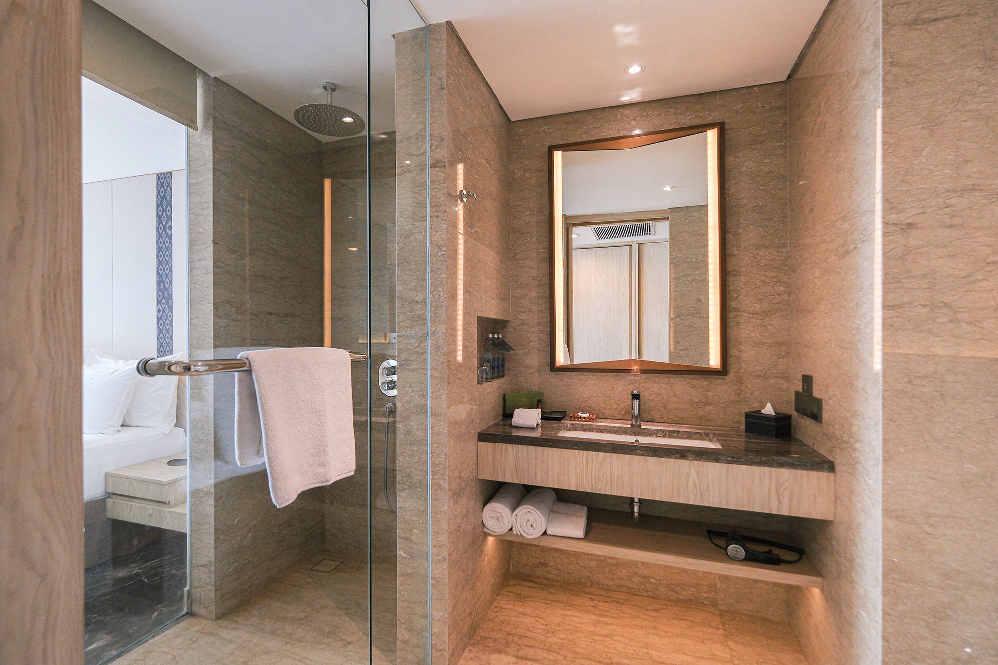 A modern bathroom with a glass-enclosed shower, a vanity with a mirror, and a towel rack.