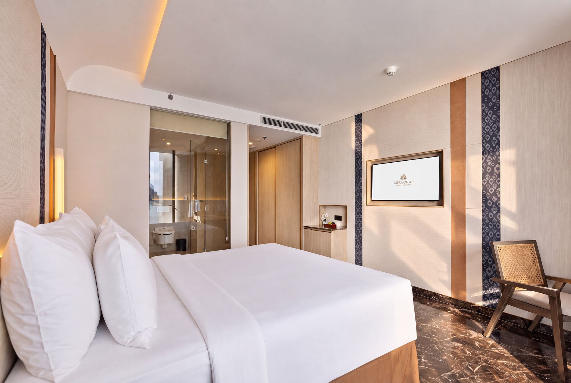 A hotel room with a bed, a shower, a vanity, and a chair.