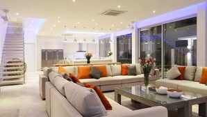 A modern living room with a large sofa set, a coffee table, and a staircase. - FREE $1600 Daily Luxury Pack - 16-Bed Beachfront Villa - Private Pool, Spa & Gym (Tambon Vichit, Ampur Muang)