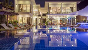A modern hotel with a large pool, multiple lounge areas, and a well-lit exterior. - FREE $1600 Daily Luxury Pack - 16-Bed Beachfront Villa - Private Pool, Spa & Gym (Tambon Vichit, Ampur Muang)