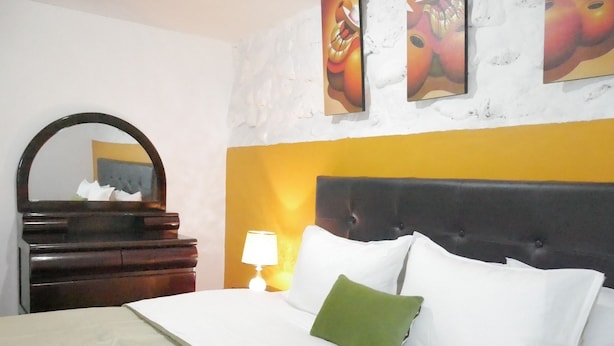 A hotel room with a bed, a dresser, a mirror, and wall art. - Cusco Dulce House Apartment (Cusco)