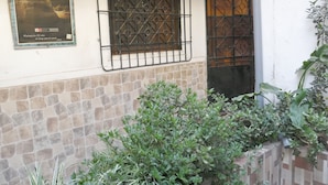 A building exterior with a stone wall, metal window bars, and a door with a decorative pattern. - Cusco Dulce House Apartment (Cusco)