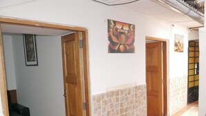 A hallway with wooden doors, a stone wall, and a tiled floor. - Cusco Dulce House Apartment (Cusco)