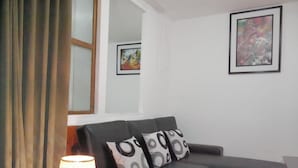 A living room with a black sofa, two patterned pillows, a lamp, and a framed painting on the wall. - Cusco Dulce House Apartment (Cusco)