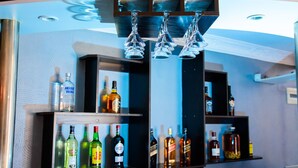 A bar area with shelves of liquor bottles and a hanging light fixture. - Hotel Restaurant Azalee (Antananarivo)