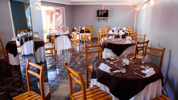 A dining area with round tables, wooden chairs, and a tiled floor. - Hotel Restaurant Azalee (Antananarivo)