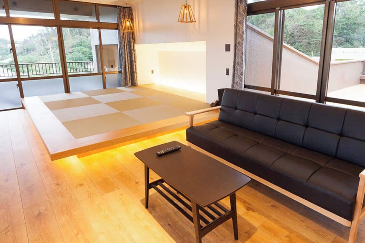 A modern living room with a sofa, a coffee table, and a tatami mat area.