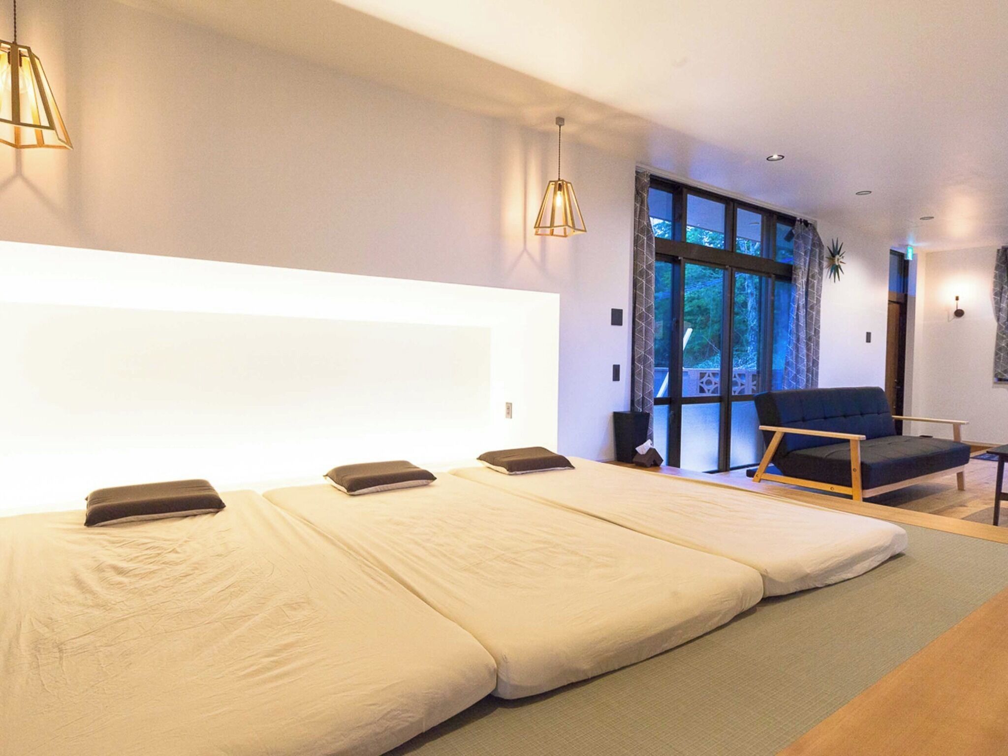 A modern room with a large bed, a sofa, and a view of the outdoors.