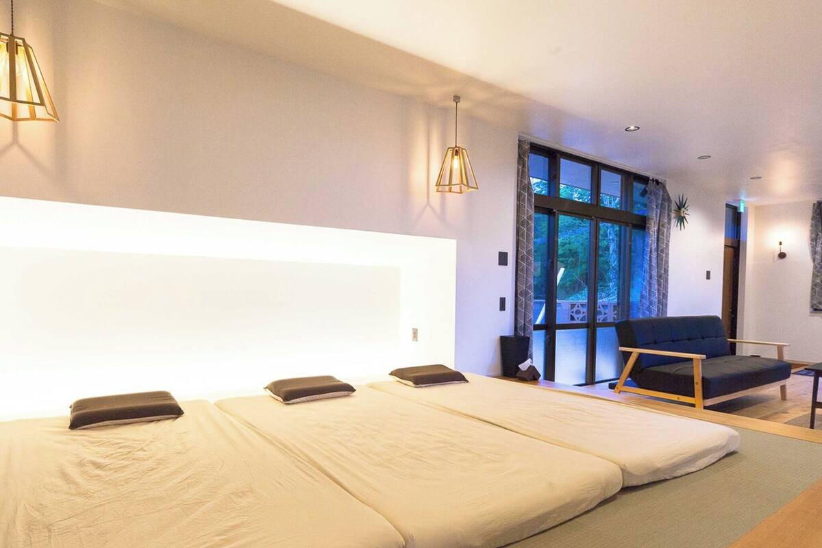 A modern room with a large bed, a sofa, and a view of the outdoors.