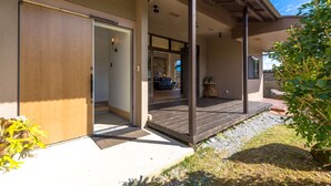 Una casa moderna con puerta de madera, un porche cubierto y un pequeño jardín.