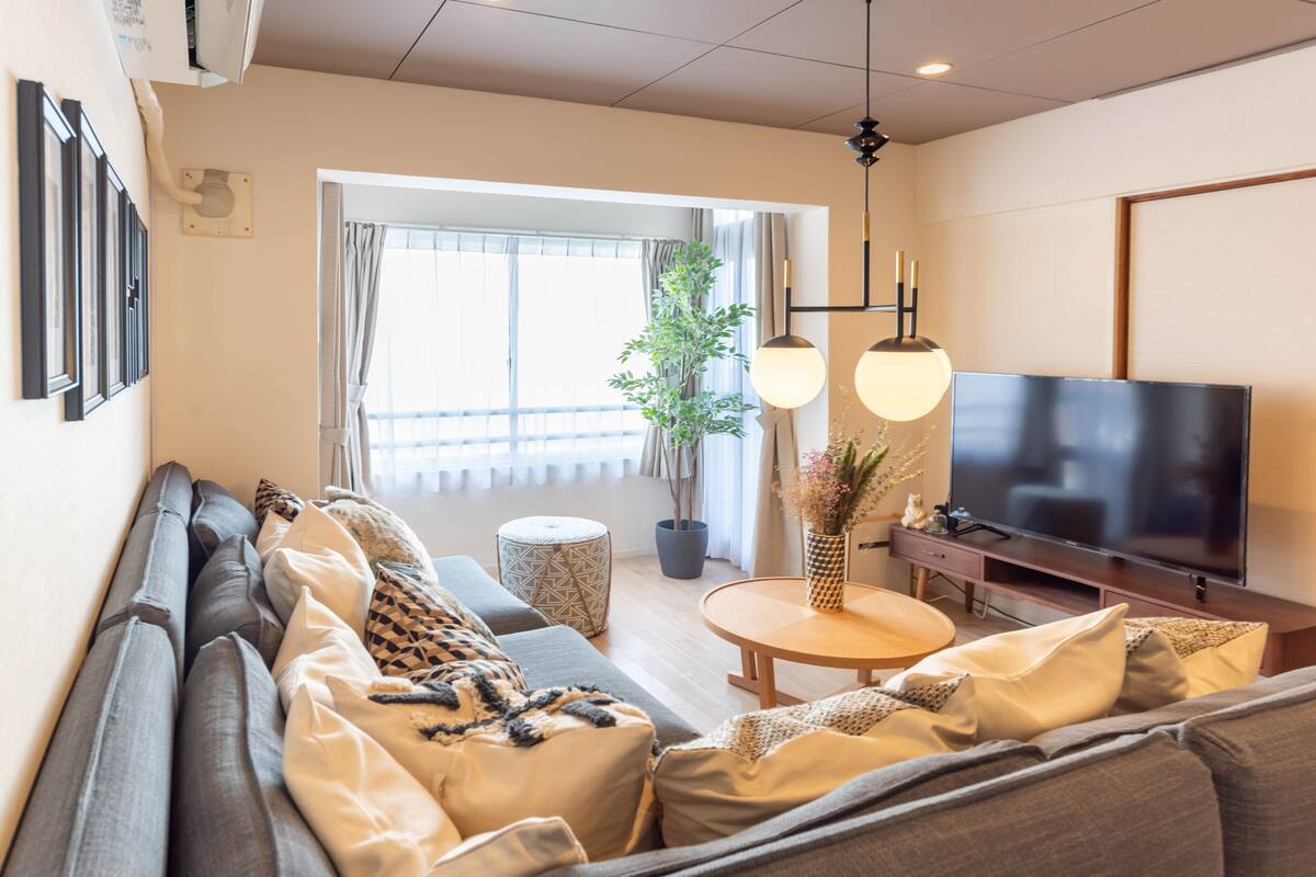 A modern living room with a sofa, TV, and a potted plant.
