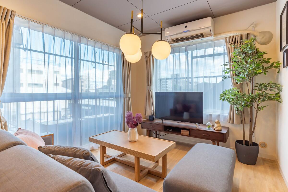 A modern living room with a sofa, a wooden coffee table, a TV, and a potted plant.