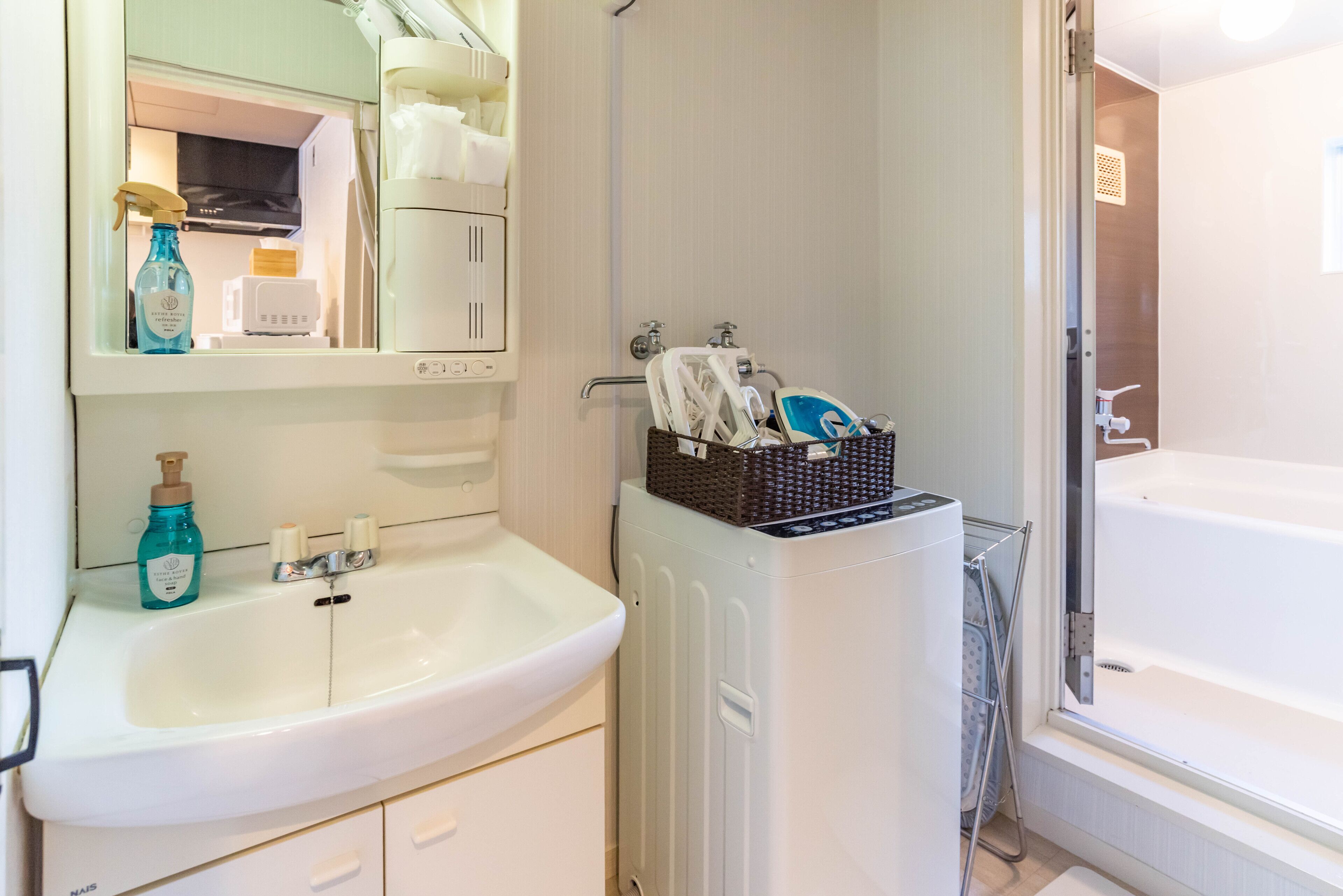 A bathroom with a white sink, a mirror, a white bathtub, and a towel rack.