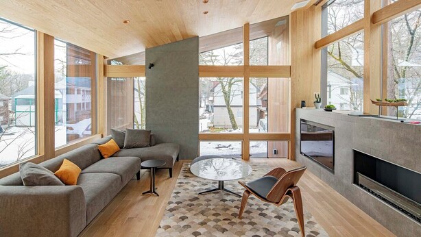 A modern living room with a large window, a grey sofa, a round glass table, and a fireplace. - Kairos by the Mountain (Hakuba)