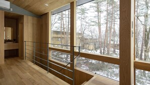 A modern interior with wooden floors, large windows, and a metal railing. - Kairos by the Mountain (Hakuba)