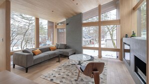 A modern living room with a grey sofa, a round coffee table, and a fireplace. - Kairos by the Mountain (Hakuba)