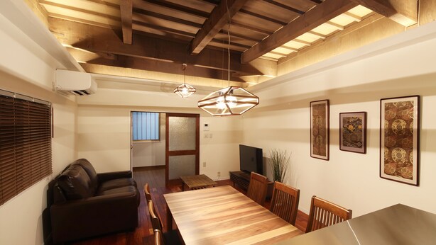 A spacious living area with a wooden ceiling, a dining table, and a sofa.