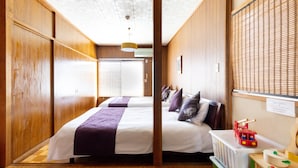 A hotel room with wooden walls, a large bed with a purple blanket, a small table with a toy fire truck, and a radiator.