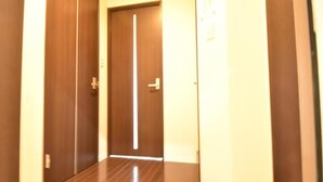 A hallway with two wooden doors, one with a vertical handle and the other with a horizontal handle. - Enzo Shin-Osaka C (Osaka)