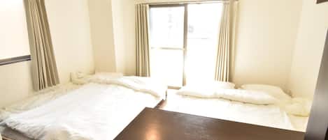 Habitación de hotel con dos camas, un escritorio de madera y un equipo de aire acondicionado.