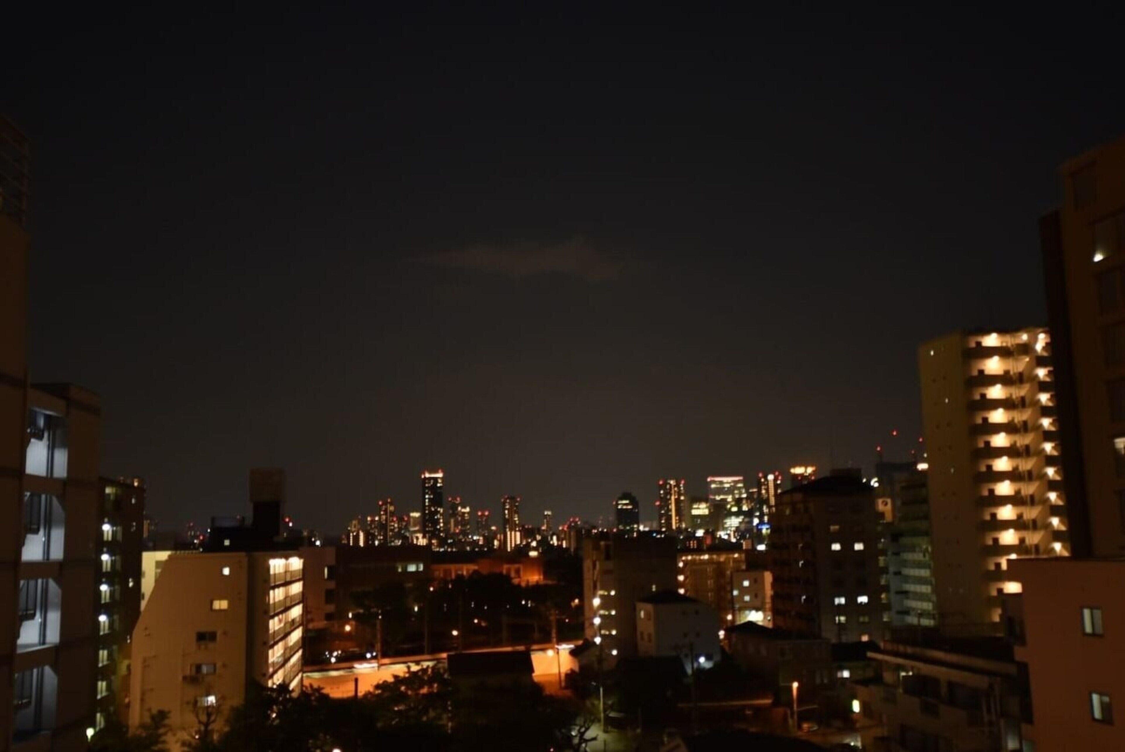 A nighttime cityscape with illuminated buildings and a dense urban environment.