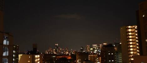A nighttime cityscape with illuminated buildings and a dense urban environment.