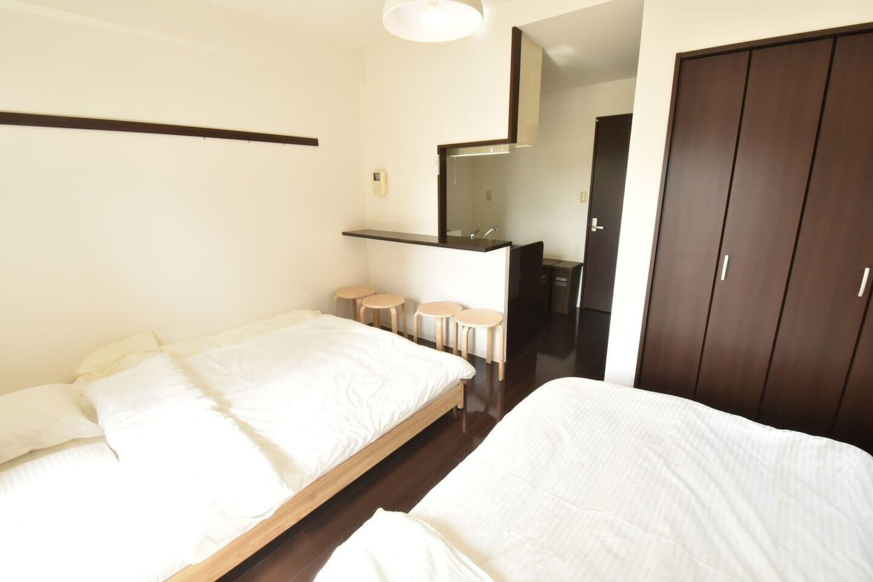 A bedroom with two beds, a small bathroom, and a wardrobe.