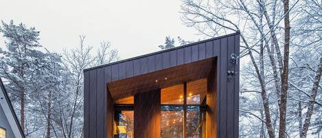 A modern, dark-colored building with a glass entrance and a wooden interior.