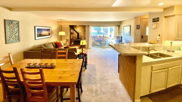 A spacious living area with a wooden dining table and chairs, a sofa, and a fireplace. - Mountain Getaway (Mammoth Lakes)