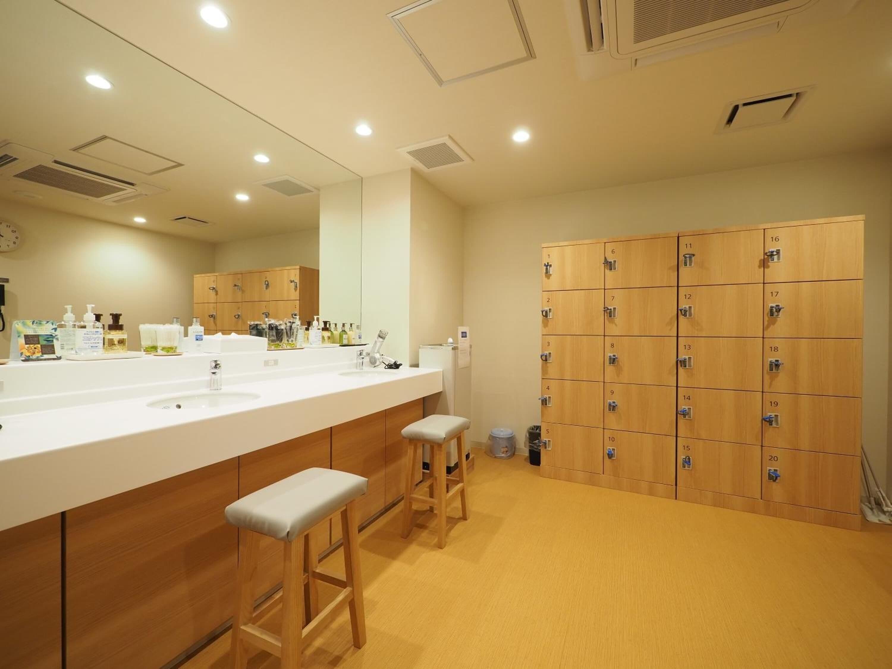 A modern bathroom with a large sink, wooden cabinets, and a row of lockers.