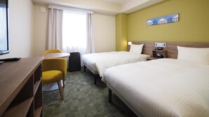Ein Hotelzimmer mit zwei Betten, einem Schreibtisch, einem Stuhl und einem Fernseher.