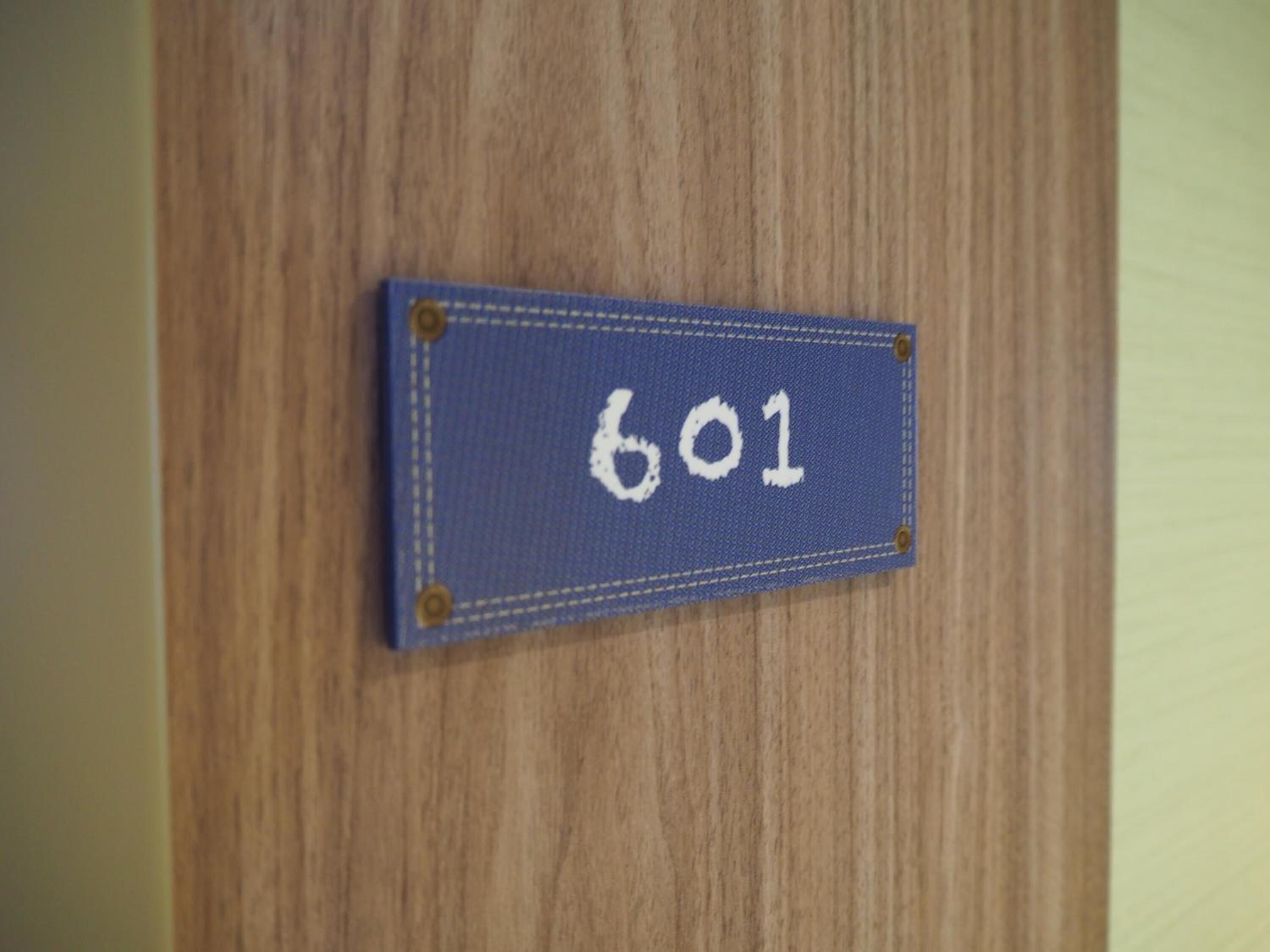 Um sinal azul com o número 601 numa porta de madeira.