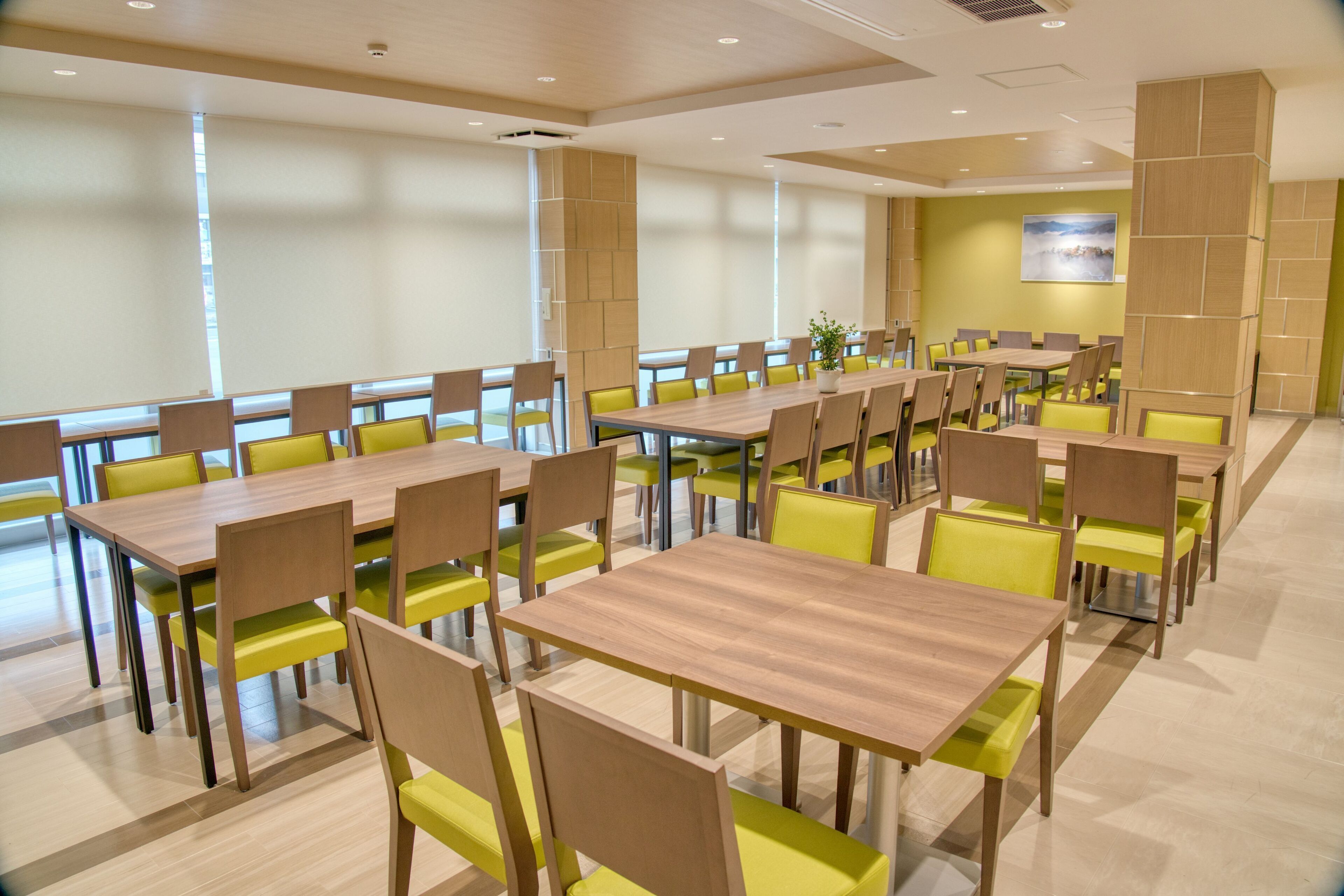 A conference room with multiple tables and chairs, large windows, and a modern design.