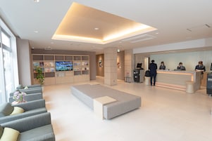 Un moderno vestíbulo de hotel con mostrador de recepción, zona de estar y una gran pantalla de televisión.