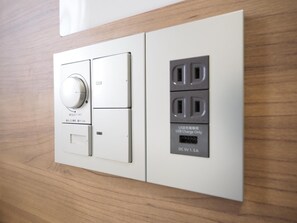Eine an der Wand montierte Stromverteilerbox mit großem Drehknopf, einem USB-Ladeanschluss und drei Steckdosen.