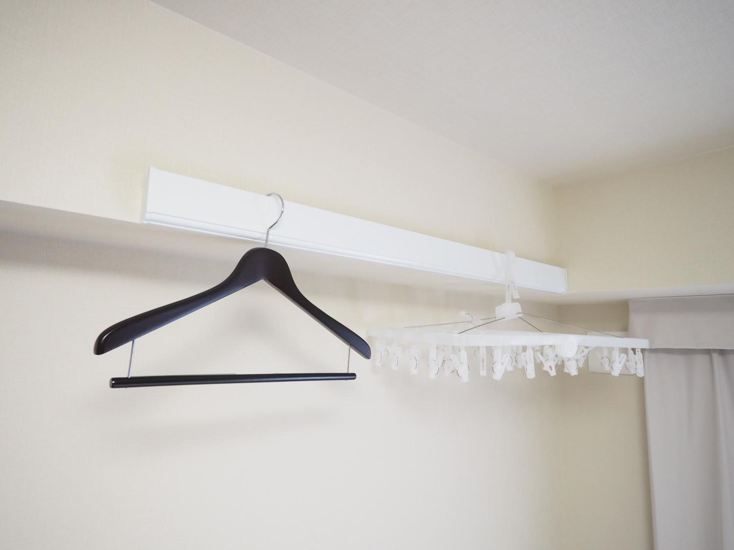 A room with a white wall, a black hanger, and a white curtain.