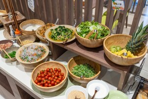 A buffet with various dishes including salads, fruits, and vegetables.