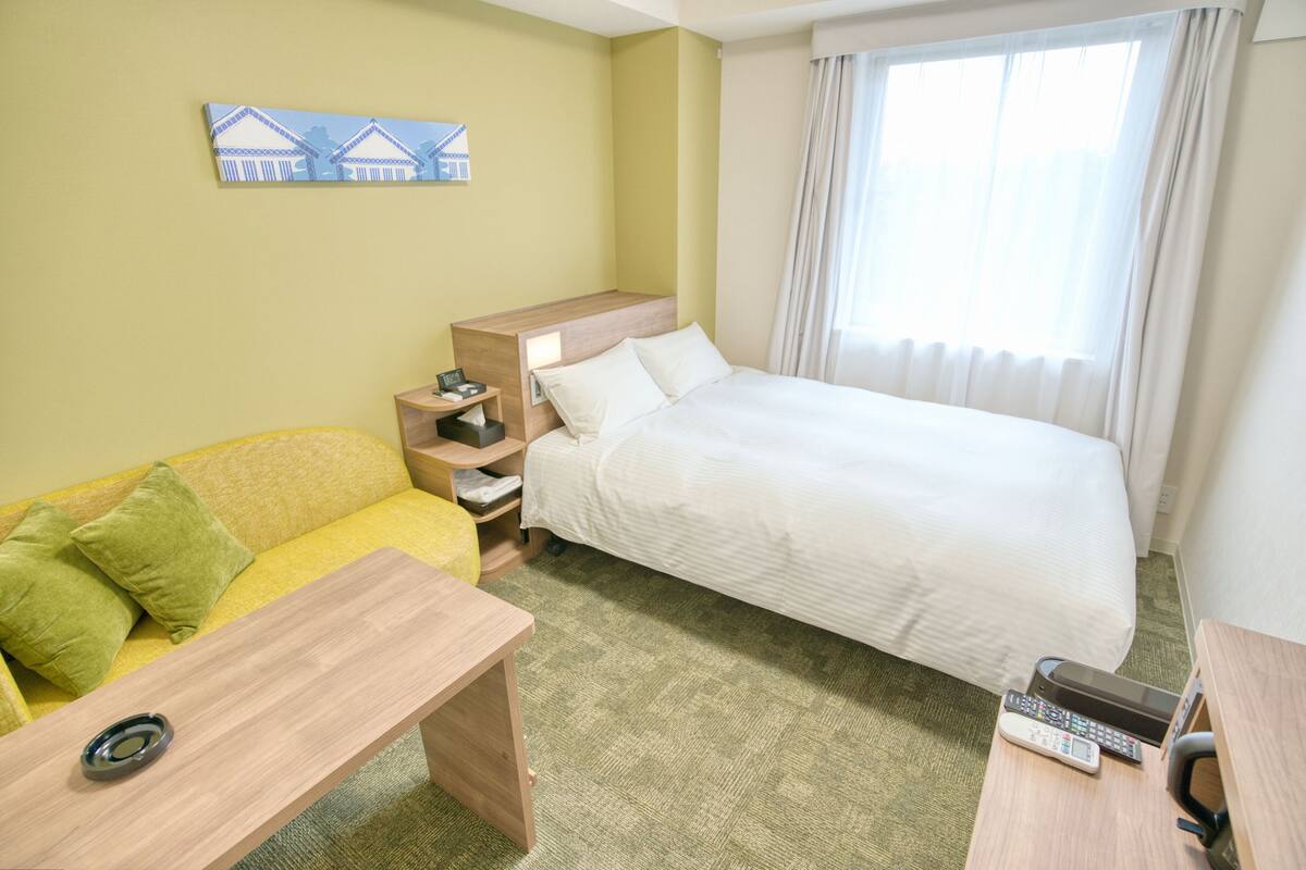 Ein Hotelzimmer mit einem Bett, einer Couch, einem Schreibtisch und einem kleinen Tisch.