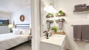 A bedroom with a bed, bedside table, lamp, and a view of a landscape painting. - Midnight Sun Retreat - Close to Trails, Shopping (Anchorage)