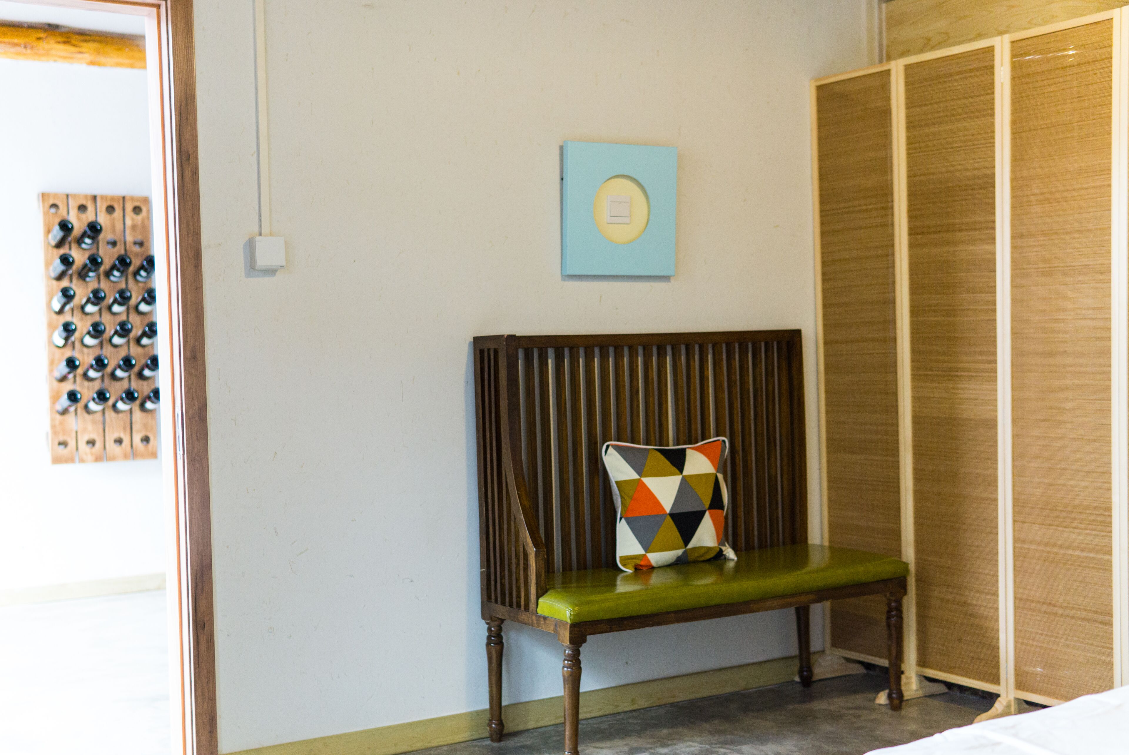 Une pièce avec un banc en bois, une armoire en bois et un interrupteur fixé au mur.