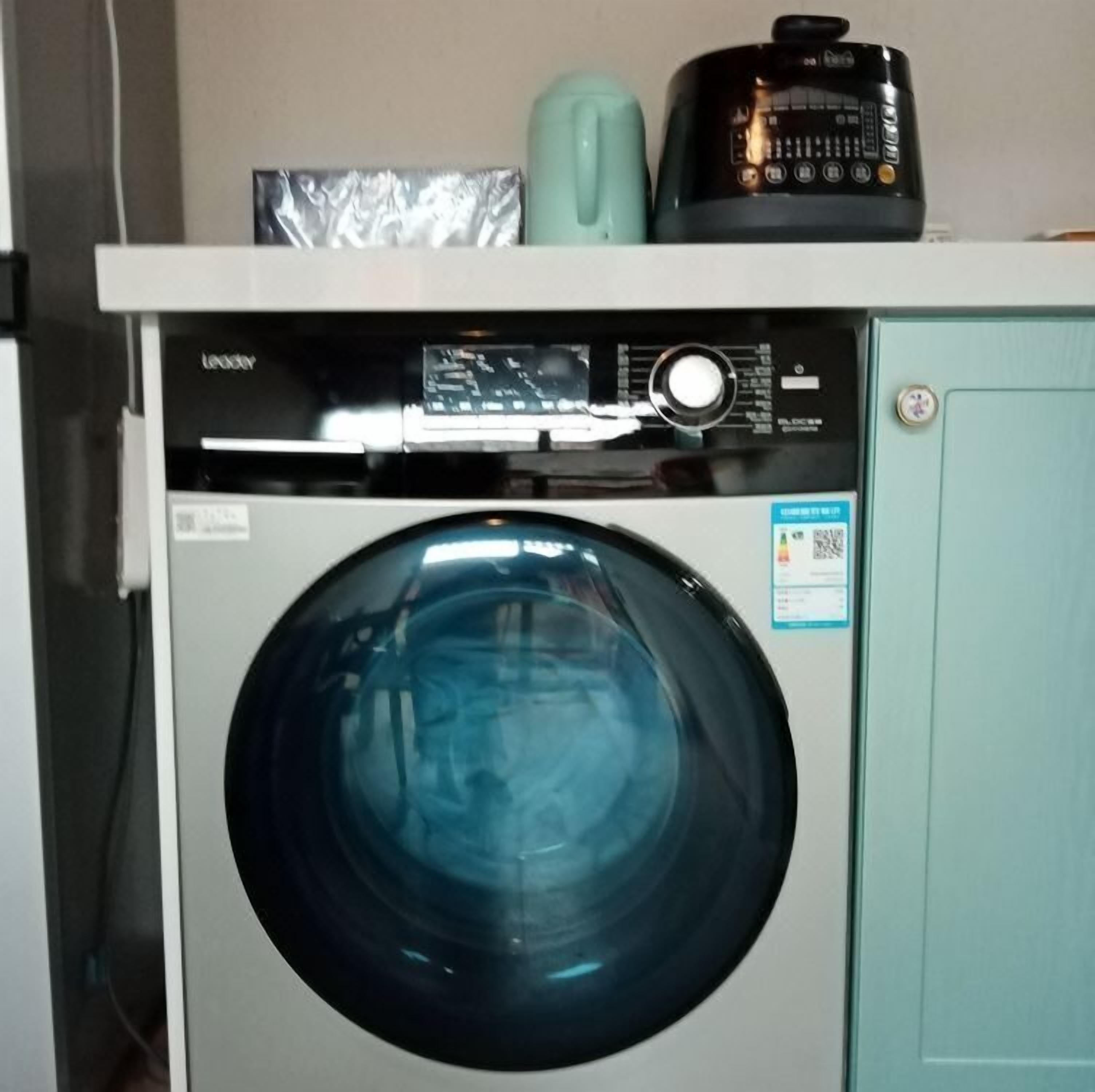 A front-loading washing machine with a control panel and a small label on the door.