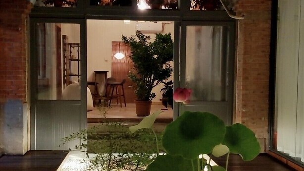 A well-lit indoor garden area with potted plants and a seating area visible through the glass doors.