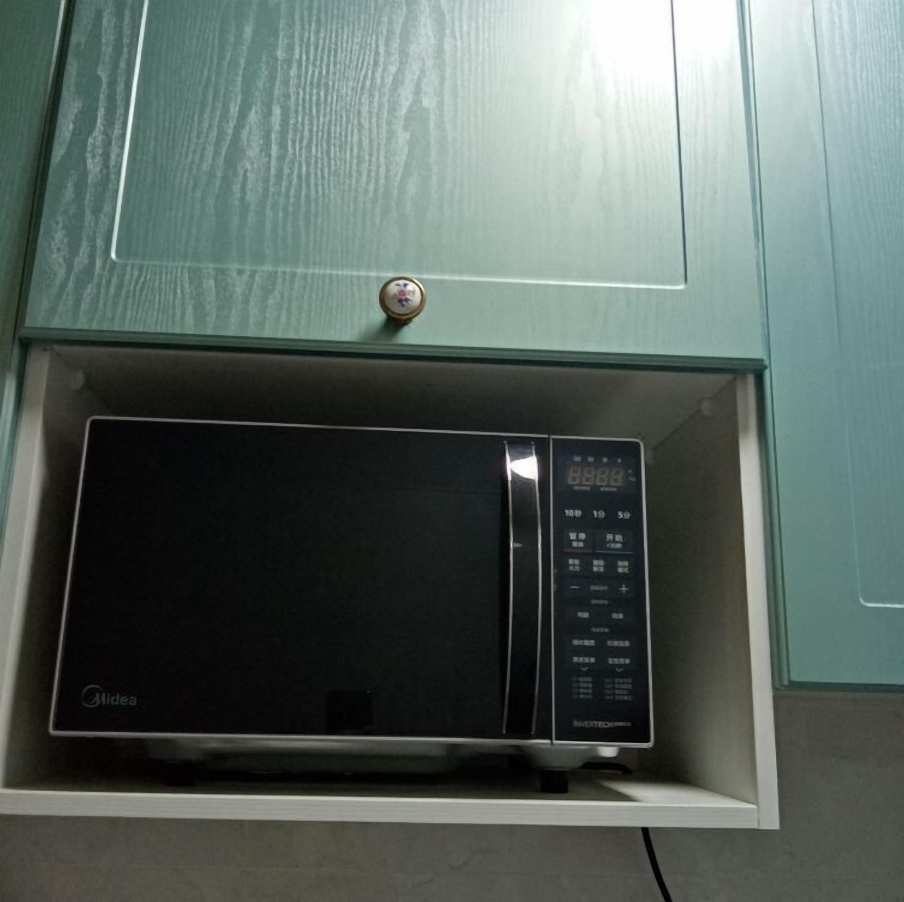 A microwave in a drawer under a cabinet.