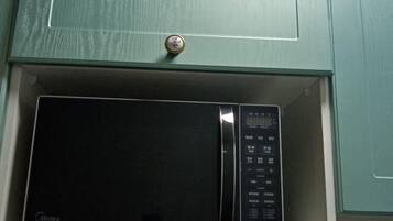 A microwave in a drawer under a cabinet.