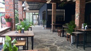 Un patio interno con pavimento in pietra, tavoli di legno e piante in vaso.