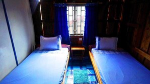 Una stanza con due letti, pareti in legno e una finestra con tende blu.